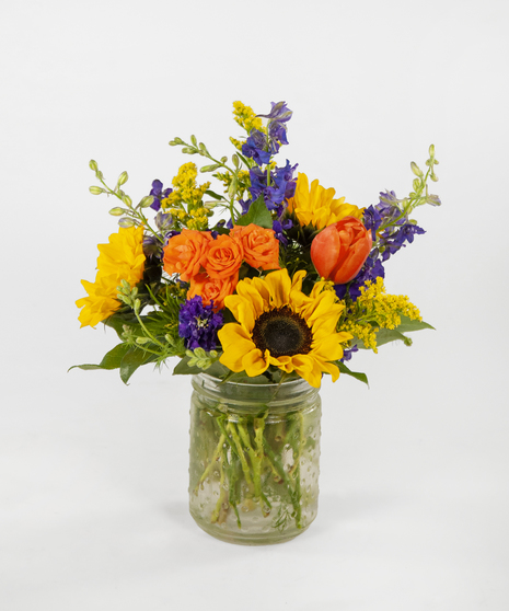 orange, purple, and yellow flowers in a cylinder vase